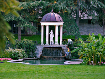 装饰喷泉与妇女和白色专栏的雕塑在公园区域的背景下