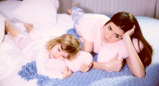 浪漫的氛围母亲和女儿在床上拥抱粉红色柔软的心