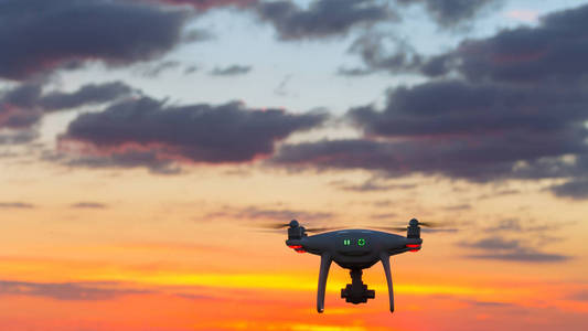 在美丽的日落美丽的天空无人驾驶飞机的背景下飞行无人机做它的工作