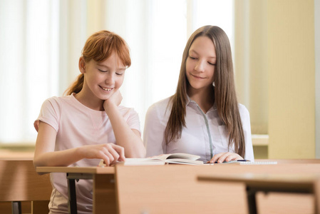 2学生女孩坐在桌旁