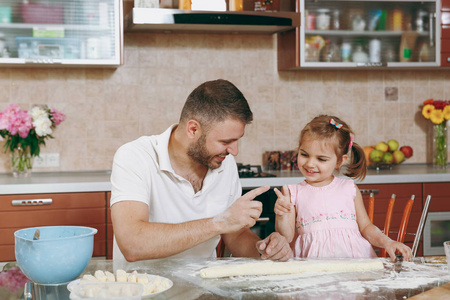 小女孩帮助男人做懒饺子, 在餐桌上玩清淡的厨房。快乐的家庭爸爸, 孩子的女儿在周末早上在家里做饭。父亲节假期。亲子童年