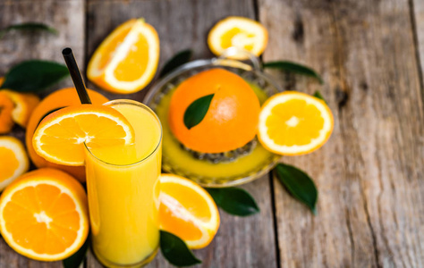 杯桔子汁和鲜橙色水果仿古木制的桌子上