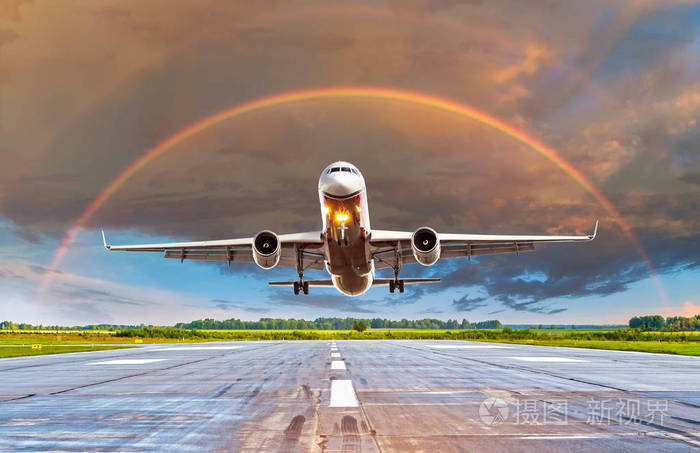 飞行中的飞机在日落和中心的彩虹在美丽的天空