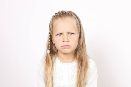 画像的悲伤和滑稽的四岁的小女孩与金发, 辫子, 身着白色衬衫, 皱着眉头不满意的面部表情。儿童女性, 独立背景, 复制空间, 特