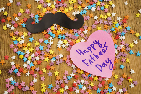 快乐的父亲日在红色贴纸和黑胡子字。木背景与许多多彩的星