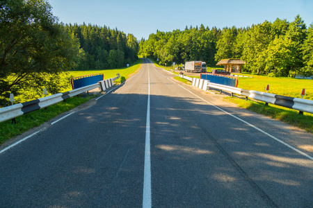 一条双车道的道路, 在明亮的绿色森林地带和蓝天照片