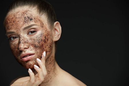 脸部护理。美丽的女子和咖啡擦洗皮肤上的特写