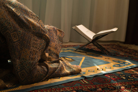 穆斯林妇女的手在地毯上祈祷传统穿着衣服, 妇女在头巾, 地毯的克尔白