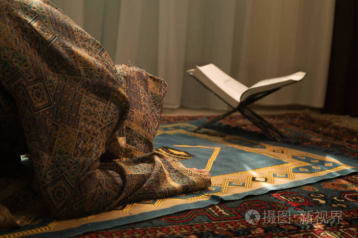 穆斯林妇女在窗口附近的房间祈祷真主的穆斯林上帝.