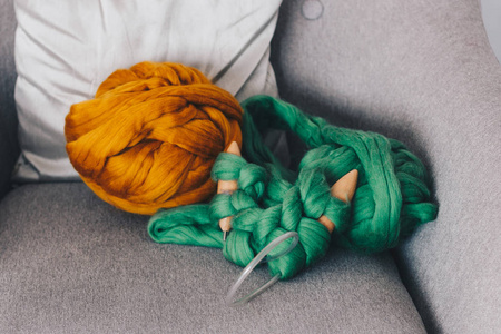 橙色的美利奴羊毛球与绿色针织毯子