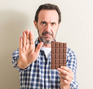 老人吃巧克力酒吧用张开的手做停止标志以严肃和自信的表达, 防御姿态