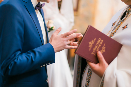 在教堂婚礼期间,牧师用手指戴上戒指新郎照片