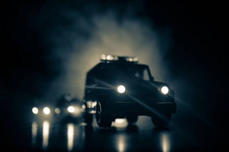 警车在晚上。警车在夜间追逐一辆汽车的烟雾背景。911紧急救援警车超速到犯罪现场。选择性聚焦