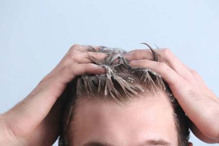 男性洗头年轻人洗头发在颜色背景, 特写照片