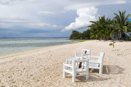 白色的桌子和椅子在海滩的沙滩上