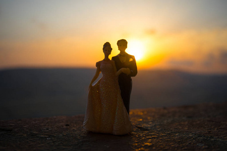 婚礼情侣雕像的剪影牵手一起在日落与黄昏的天空背景。婚礼的概念。选择性聚焦