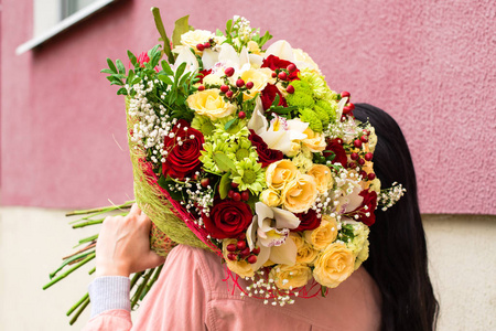 女人收到一束美丽的红色和米色的玫瑰花束, 白菊