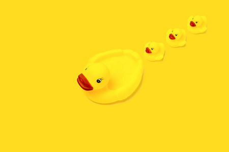 黄颜色的橡胶玩具鸭妈妈和小鸭子在黄色背景。母亲关爱和关爱儿童的概念。平躺, 顶部视图