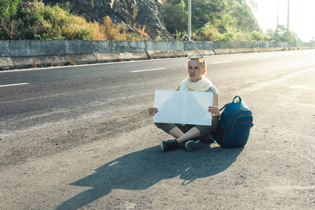 年轻女子搭便车的人坐在路边图片