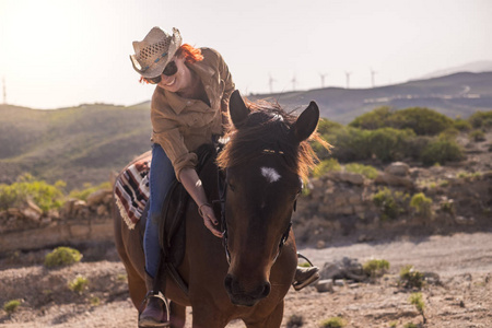 年轻的红色头发妇女骑在棕色马户外在白天照片