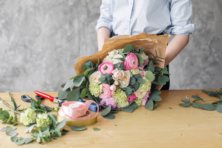 花店里的女花商创造美丽的花束。在花店工作。在花卉设计工作室的女孩助理或业主, 作出装饰和安排