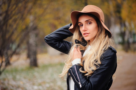 秋季帽子时尚秋画像年轻快乐的女人走在秋季公园的帽子和皮革夹克户外