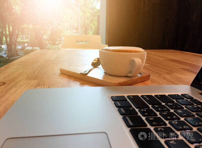 咖啡杯和内咖啡厅的木桌上的笔记本电脑.经营理念