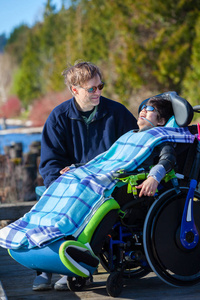 残疾的男孩，坐在轮椅跟父亲在湖滨公园