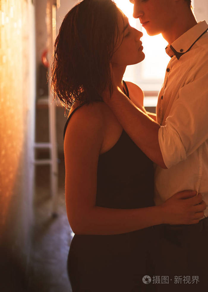 年轻人在晚上在夕阳的光线在公寓中拥抱