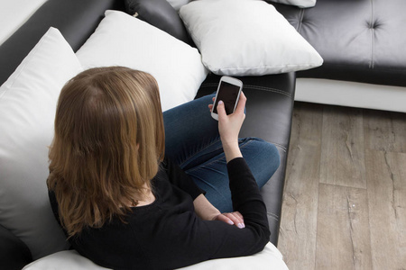 年轻的女人用她的智能手机的鸟瞰图照片