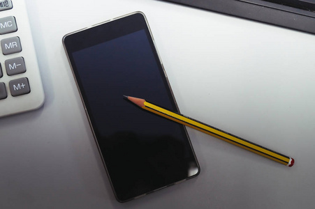 简单的黑色和黄色铅笔在白色背景智能手机。侧面拍摄。技术, 社会媒体, 编程, 数学, 商务办公室概念