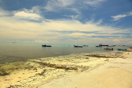 美丽的海岸线, 印度洋, 马尔代夫的景色。白沙海岸, 黑暗的水面, 几艘船和小船遥远。美丽的自然风景背景