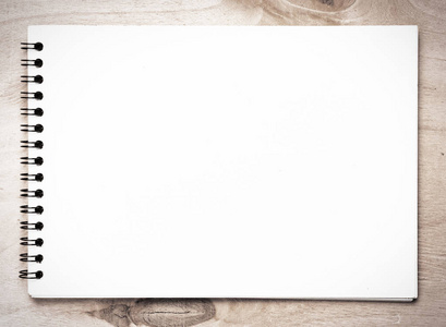 原木桌面背景上的螺旋空白笔记本的顶部视图照片