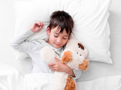 儿童男孩抱着长毛绒玩具睡觉图片