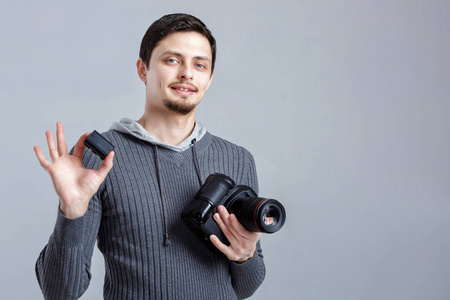 年轻微笑摄影师在衬衫拥有单反相机电池