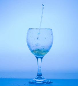 在蓝色玻璃用滴的白葡萄酒中突出显示照片