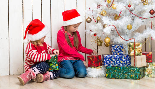 两个小女孩打开圣诞礼物坐在地板上