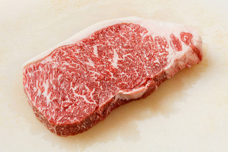 关闭神户牛肉 striploin 牛排在肮脏的塑料切割板上