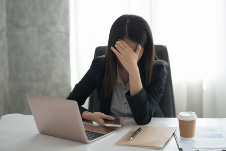 年轻的亚洲女商人在上班时感到压力/担心/头疼/失望疲劳的女人睡不着