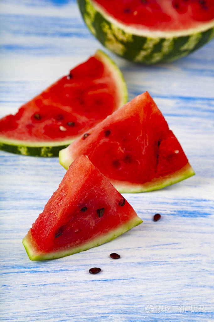 一块西瓜放在一张蓝色的木桌上.美味甜点