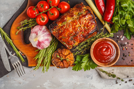 烤猪肉用百里香, 迷迭香, 大蒜和番茄酱在木板上, 浅色背景, 复制空间