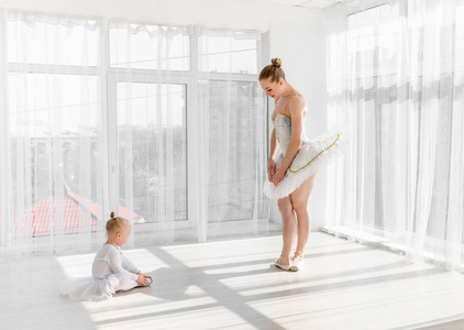 年轻华丽的芭蕾舞演员与她的小女儿在演播室跳舞