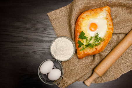 格鲁吉亚的菜。顶视图的 khachapuri 上麻布 面粉 鸡蛋和擀面杖。黑色的桌子，文本的空间