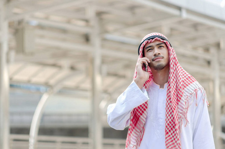 年轻的阿拉伯商人在 c 步行时使用移动电话