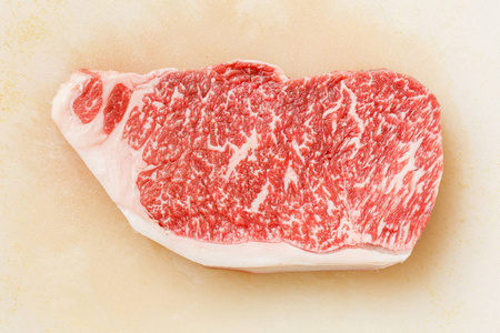 关闭神户牛肉 striploin 牛排在肮脏的塑料切割板上