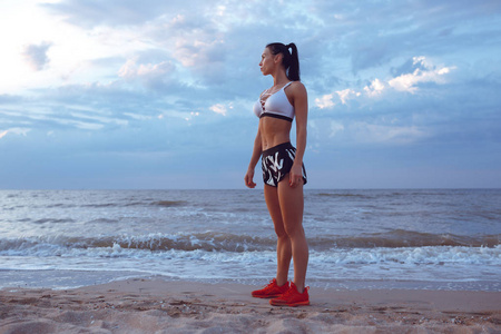 这个女孩做热身运动之前, 清晨在海边做体育运动。体育锻炼的女孩, 肌肉发达