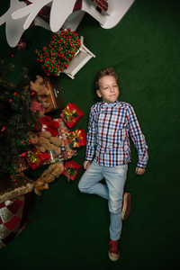 男孩躺在圣诞树旁边的礼物