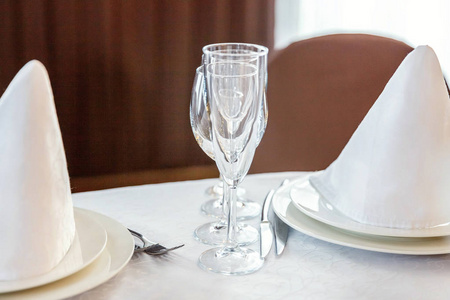 眼镜, 餐巾折叠在一个金字塔, 服务于晚餐在餐厅与舒适的室内。婚礼装饰品和食物用品, 由餐饮服务安排在一个大桌子上, 上面铺着白