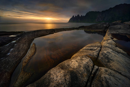 Tugeneset 岩石海岸与山在背景在日落, Senja, 挪威