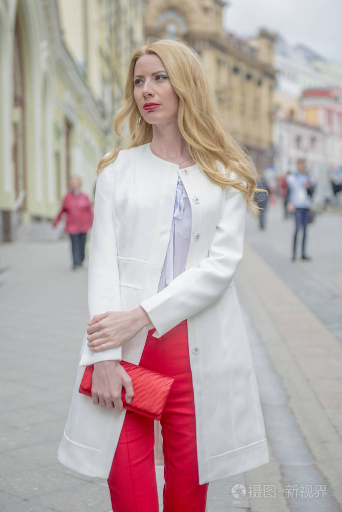 时尚年轻的金发女郎在一个春季时髦的西装和一个购物袋在莫斯科中心